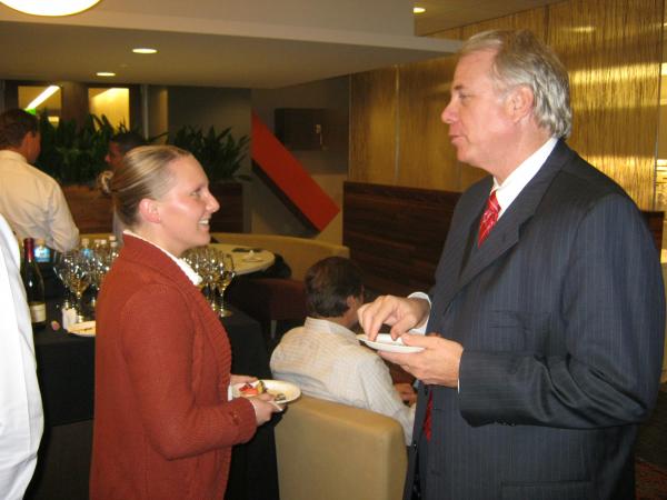 A man and woman are standing and talking while holding plates of food