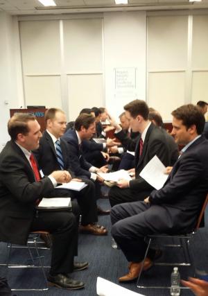 Two rows of men in suits sitting in chairs facing each other