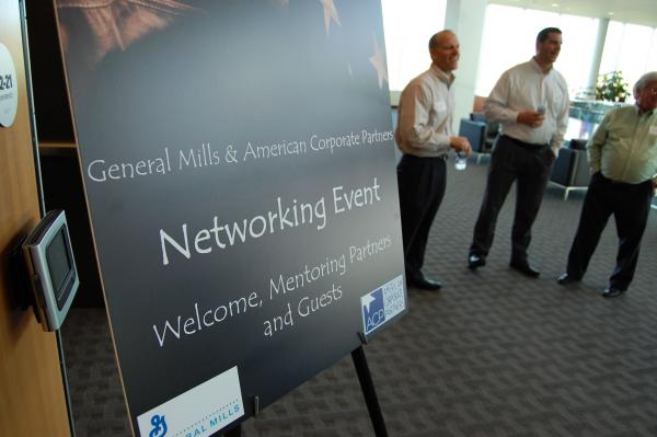 Welcome sign in foreground,  attendees socializing in background