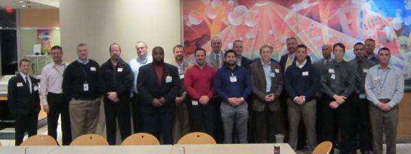 19 of the attendees posing for a photo in front of large abstract painting