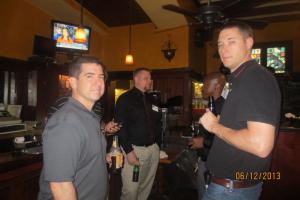 two men,each holding a beer bottle, talking