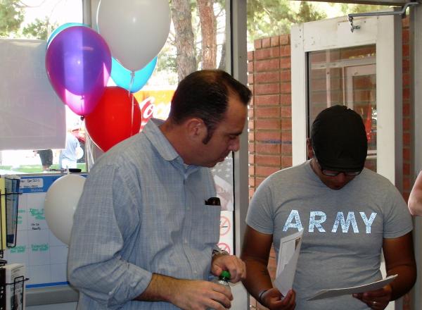 2 men standing looking at paperwork - balloons in background