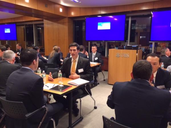 people sitting in a large room, at tables for two, talking